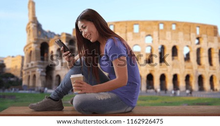Happy Japanese female drinking coffee and texting her boyfriend near Coliseum