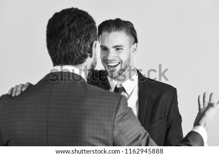 Business and friendship concept. Successful negotiations between businessmen. Boss and employee speaking at meeting on light background. Man with happy face in jacket listening his business partner.
