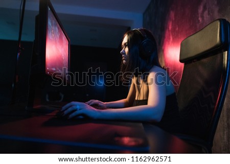 girl gamer in headphones and with a keyboard and mouse in her hands playing network games preparing to participate in international competitions in e-sports