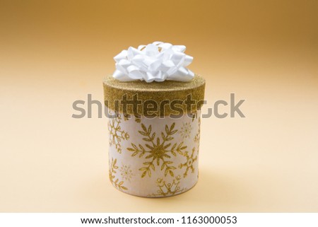 Christmas white gift box with golden glitter pattern, decorated with a white bow, creating a romantic atmosphere. Typically used for birthday, anniversary presents, gift cards, post cards. 