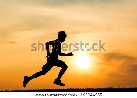 Photograph of an athletic boy silhouetted against the sunset runs on a field in north Idaho. Royalty-Free Stock Photo #1163044555