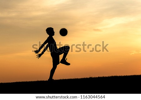 A concept photograph of a young athlete silhouetted against the sunset practices soccer.