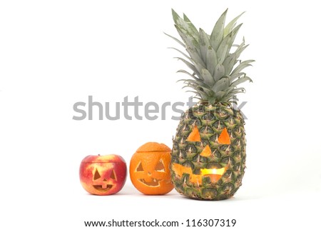 Jack-o-lanterns made from pineapple, apple and orange creating tropical halloween decoration