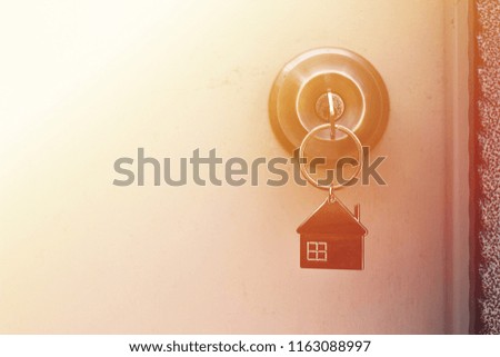 Property Concept, Home key with metal house keychain in keyhole.