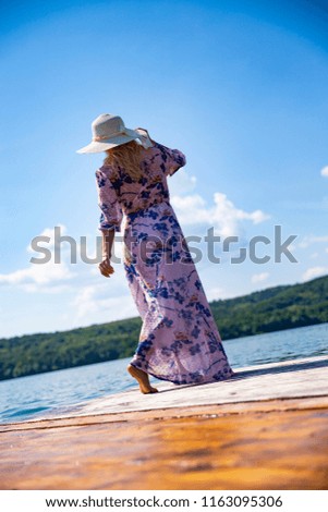 Girl in a white hat. A girl in the style of Provence. The girl is waiting on the beach. The girl is holding her white hat.