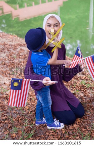 Beautiful hijab malaysian/asian mother and her cute boy spending time together celebrating Malaysia Day at park. Relationship of mother and son concept. Family concept.
