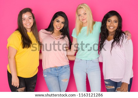 Group of four teen girls having fun together on a pink background