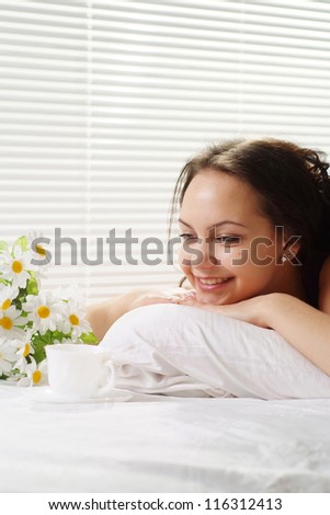 Nice Caucasian female lying in a bed of cup on a light background