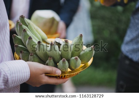 One man holds a banana on a gold tray.