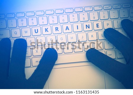 UKRAINE inscription on laptop keyboard. Hacker man using a laptop attacks the web. Cyberattack, online theft of personal data and cybercrime concept 