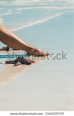 Girl sitting on the beach with starfish in Zanzibar