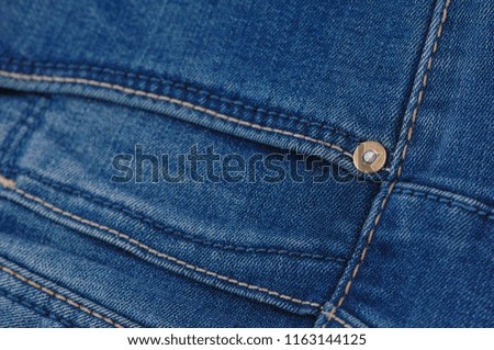 part of the blue denim pants with pockets and rivets, close-up
