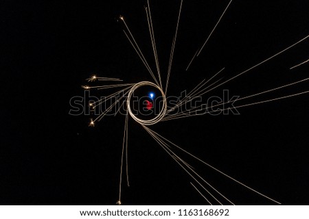 Aerial view of man spinning burning steel wool. Showers of glowing sparks from spinning steel wool. Drone view.
