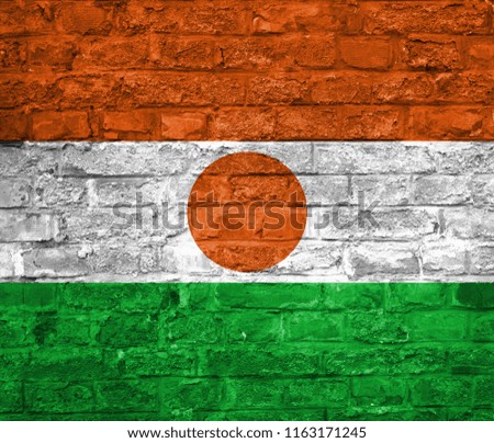 Flag of Niger over an old brick wall background, surface