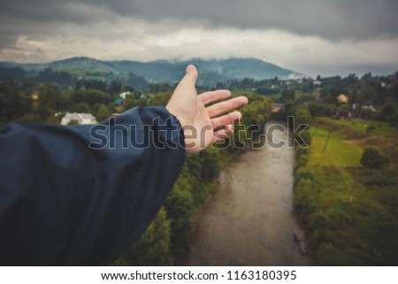 Hand in the background of a mountain landscape