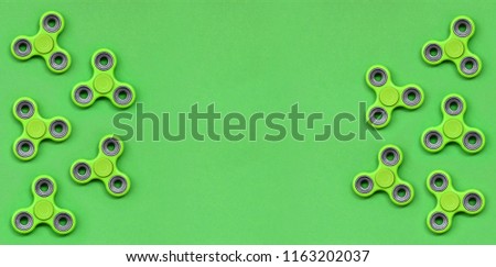 Many green fidget spinners lies on texture background of fashion pastel green color paper in minimal concept.