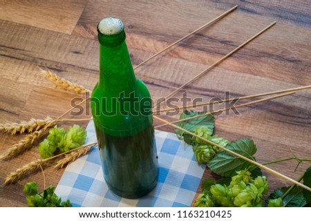 still life: beer in a bottle, cheese, malt, hops on a napkin in the color of oktoberfest