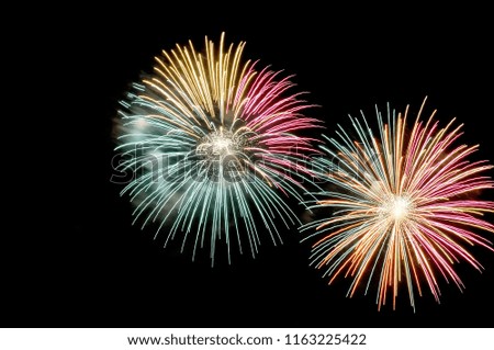 Flashes of multicolored fireworks on black background.