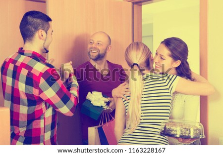 Happy smiling guests with presents and cake standing in doorway. Focus on girl