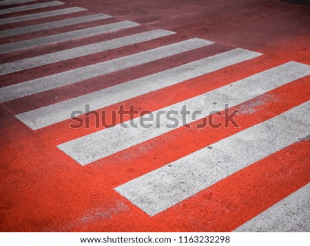 Red​ Crosswalk on the road, Pedestrian crossing with red and white stripes without people close up. The concept of safety on the road.