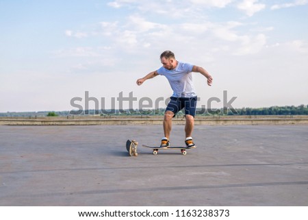 Young skateboarder performing a flip trick in a jump on the road, the free space. The concept of an active way of life.