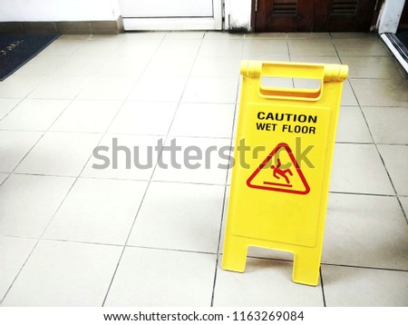 Cleaning progress caution yellow sign that alerts for wet floor in public toilet.
