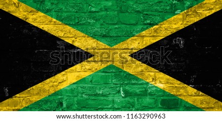 Flag of Jamaica over an old brick wall background, surface.