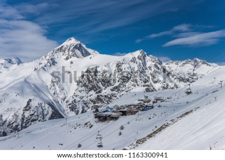 Cafe and restaurants on a ski slope in winter sunny day against Mt. Semenov-Bashi. Dombay ski resort, Karachai-Cherkess, Western Caucasus, Russia.