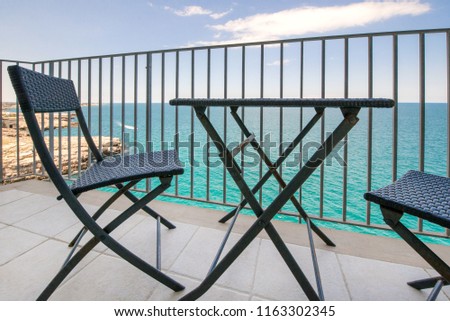 Braided modern garden furniture set on a sea side cliff balcony with a view of the horizon. 
