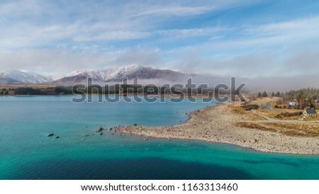 Blue Lake and a snow mountain behind and fog on the mountain, blue sky. Stunning shot mountain Aerial View at Lake Tekapo, New Zealand.
