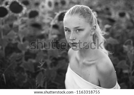 Close up portrait of young blondie freckled caucasian model in field of sunflowers