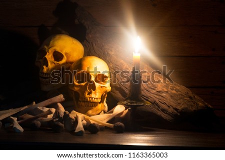 Pile of skulls and bones in the candle light,Halloween concept, still life and dim light