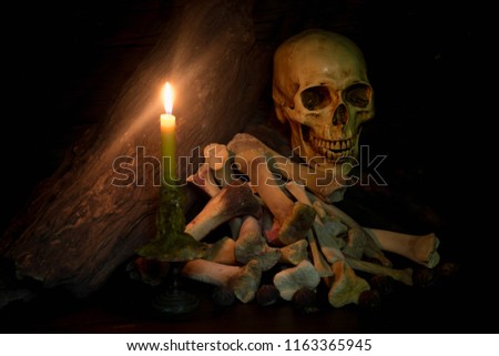 Pile of skull and bones in the candle light,Halloween concept, still life and dim light