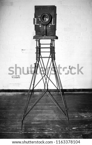 An vintage black and white camera on a metal stand 