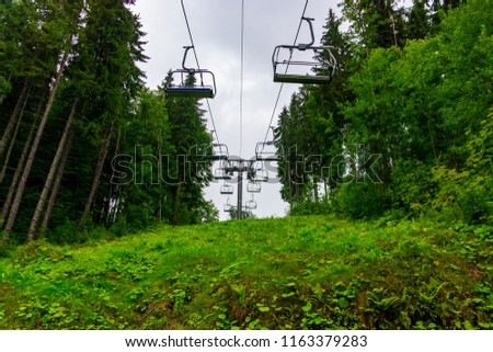 Ski chairlift in the rainy summer mountains through amazing fabulous moutain forest in Bukovel, Ukrainian Carpathians