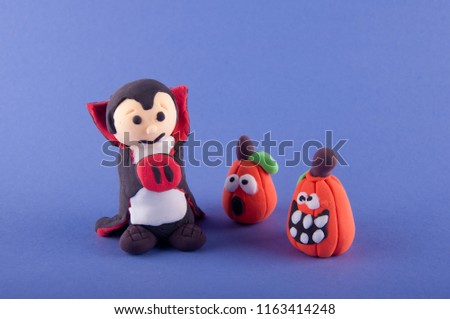 Funny halloween figures made of playing clay. Vampire and two pumpkins staying on purple background