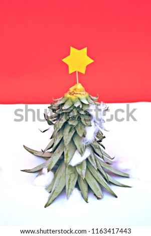 A pineapple's stalk becomes a Christmas tree with a yellow star on top - concept for Christmas with space for text or elements in front of a monochrome background