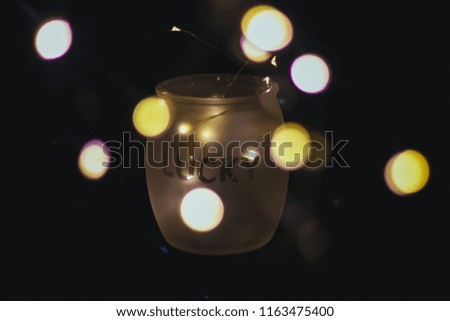 Abstract for Led Light in sparkling bokeh lights in Dark background. Low key fairy lights in mason jar with text "Lucky" for made gift and card background. selective focus.Vintage film Tone.