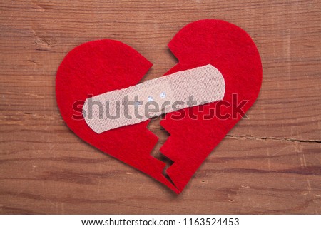 Broken red heart on wooden background.