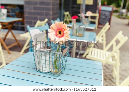Cute cozy outdoor cafe, with gerbera flower on the table