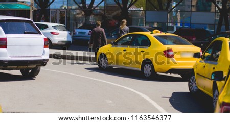  A Parking lot reserved car taxi is parked in front of a shopping center site in the city. Concept of transporting people in yellow cars . Taxis wait for passengers  . Part of public Uber transport