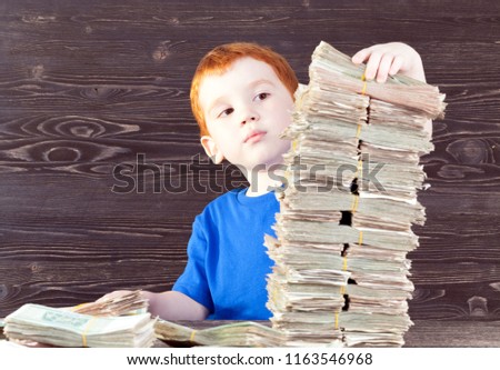 a boy in a blue T-shirt that builds out of a large number of packs of money old and poor state of the tower, a game of finance in childhood, close-up