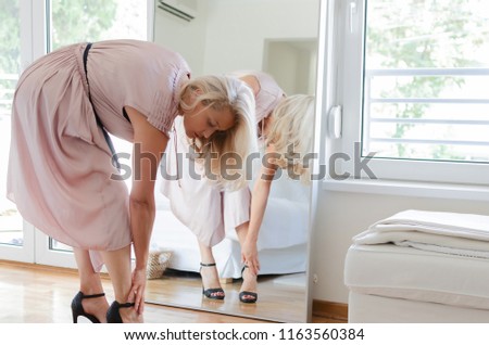 Senior woman getting ready for night out, wearing a pink dress.