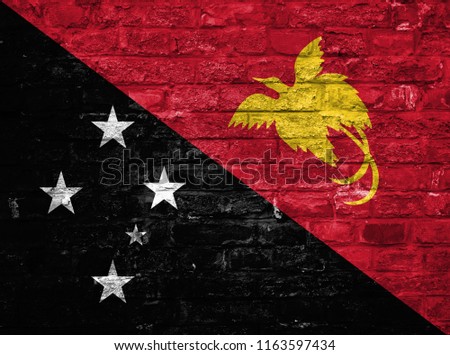Flag of Papua New Guinea over an old brick wall background, surface.