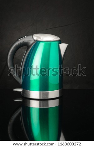 Green painted stainless steel electrical kettle on black mirror background