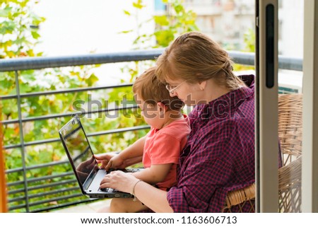 happy grandmother with grandson with laptop on balcony