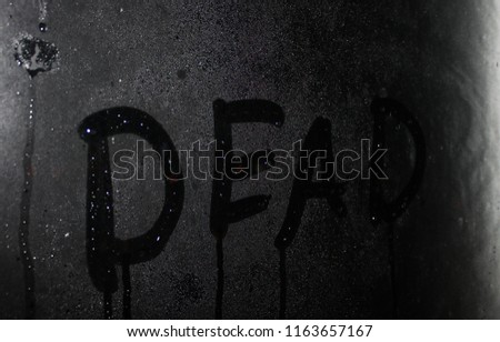 dead, a word drawn on glass on a rainy day
