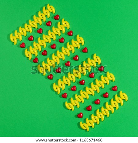 Pattern of candy bananas and heart on green background.