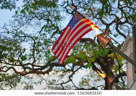 American flag of the United States of America  floating above a tiki torch