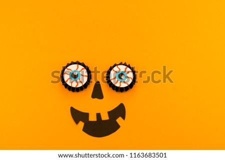 Eyes of a pumpkin monster from a paper against an orange background. Copy spase. Party holiday Halloween.